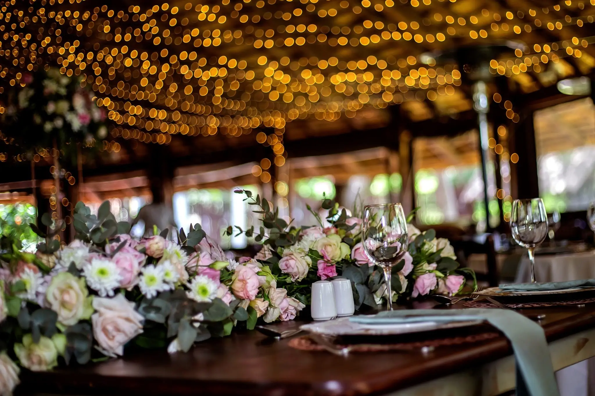 A wedding reception under a thatched roof strung with lights